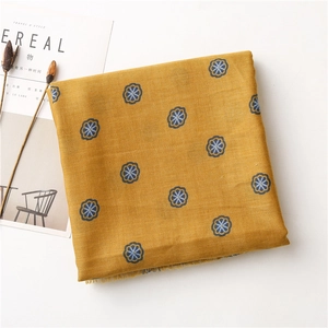 Detailed view of yellow cotton linen scarf with blue floral prints and frayed edges