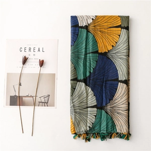 Detail of colorful ginkgo leaf print scarf with fringe tassels on white background