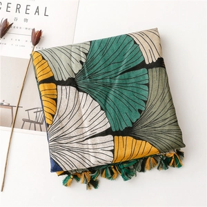 Detailed view of artistic ginkgo leaf print scarf with colorful fringe on cotton-linen fabric