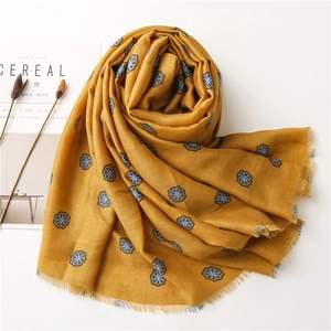 Detail of yellow cotton linen scarf with blue floral prints and soft frayed edges