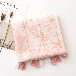 Dettaglio di sciarpa in cotone rosa con strisce di paillettes dorate e bordi a nappa