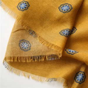 Detail of yellow cotton linen scarf with blue floral pattern and fringed edges texture