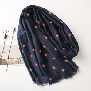 Close-up of navy blue linen scarf with red floral print and natural fringe details
