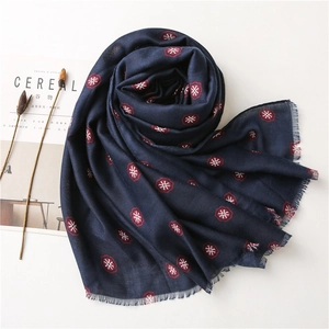 Detail of navy blue linen scarf with red snowflake prints and frayed edge craftsmanship