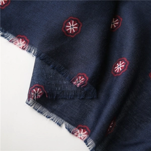Close-up of navy blue cotton linen scarf with red floral prints and frayed tassel edges