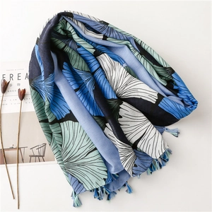 Detail of ginkgo leaf print scarf with fringe tassels on minimalist magazine background
