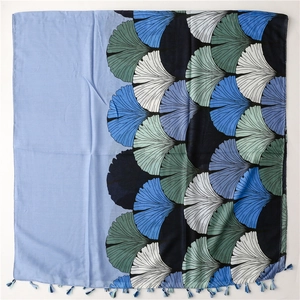 Detail of linen-feel shawl featuring blue and grey ginkgo leaf prints and tassel fringe
