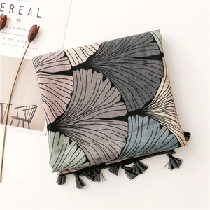 Detail of ginkgo leaf print scarf with multi-color tassels on a minimalist background