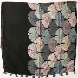 Detailed view of vintage ginkgo leaf print and fringe tassels on a soft black scarf