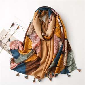 Detail of vintage ginkgo leaf print scarf with colorful short tassels on soft fabric