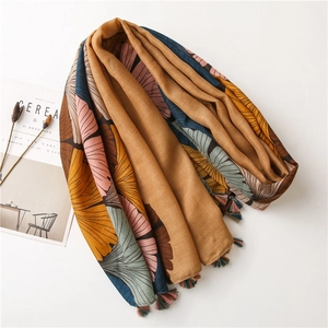 Detail of vintage gingko print scarf with colorful tassels on ginger background