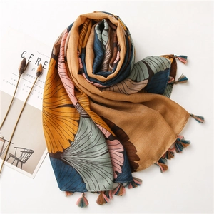 Artistic layout of yellow ginkgo leaf print scarf with multi-color tassel edge details