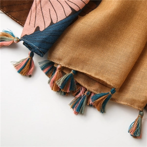 Close-up of cotton linen scarf showing ginkgo print, fabric texture, and colorful tassels