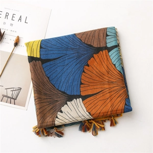Detail of artistic ginkgo leaf print scarf with colorful tassels on cotton linen texture