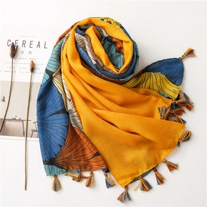 Detail of artistic ginkgo leaf print scarf with vibrant colored tassels and soft texture