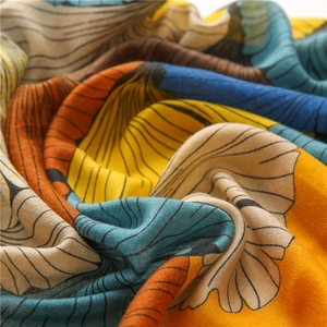 Macro shot of artistic ginkgo print scarf featuring orange and blue fan patterns