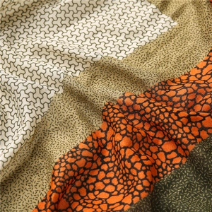 Détail d'une écharpe douce à imprimé léopard avec textures patchwork orange et olive