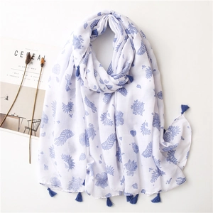 Détail d'écharpe en coton et lin blanc avec imprimé floral bleu et franges sur magazine