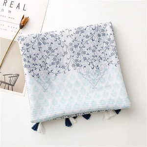 Detailed close-up of a floral cotton linen scarf with blue tassels and geometric patterns