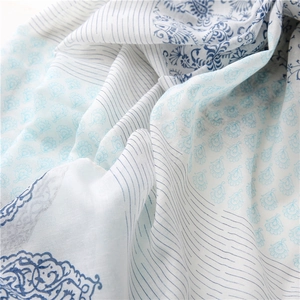 Close-up of soft white cotton shawl featuring light blue floral and paisley patterns