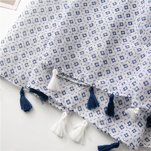 Detail of floral linen scarf with blue flower pattern and fringe tassel edges