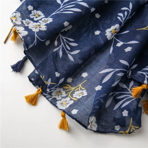 Detail of bohemian cotton linen scarf with floral print and decorative fringe tassels