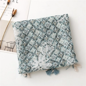 Close-up of geometric pattern blue scarf with delicate fringe tassels on white desk