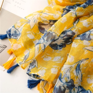 Detailed macro view of yellow cotton scarf with blue floral prints and bicolor tassels