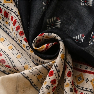 Detail of soft black and beige cotton-linen scarf with geometric floral print and fringes