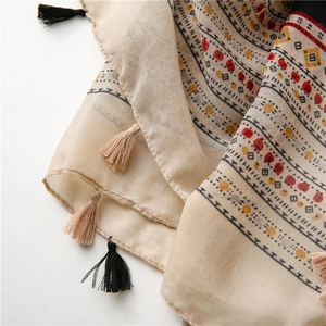 Macro detail of breathable cotton-linen scarf fabric with bohemian tassels and prints