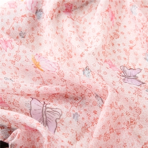 Macro shot of light pink cotton linen scarf featuring butterfly and floral print texture