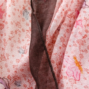 Close-up of pink linen scarf fabric featuring floral butterfly prints and brown piping detail
