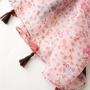 Detail of floral linen scarf with butterfly prints and alternating tassel fringes