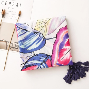 Detail of colorful leaf pattern scarf with dark blue fringe on a white minimalist background