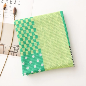 Detailed flat lay of green plaid scarf with polka dots next to a minimalist magazine