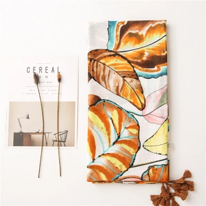 Macro view of cotton scarf with colorful leaf patterns and brown tassel trim details