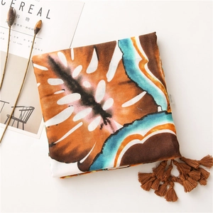 Detail of leaf print scarf with tassels alongside a lifestyle magazine and dried flowers