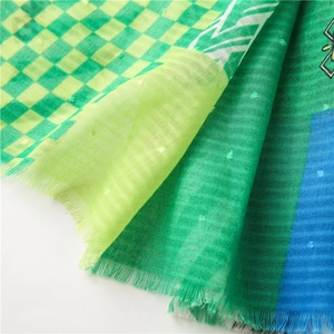 Detail of colorful plaid scarf fabric showing raised dot texture and fringed edges