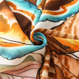 Detail of colorful leaf pattern fabric scarf with soft texture and vibrant orange blue tones