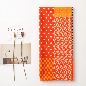Detail view of colorful plaid linen scarf with warm orange tones and geometric patterns
