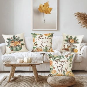 Set of four autumn pillow covers with pumpkin and orange prints on a white sofa
