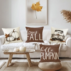 Set mit vier Herbst-Kissenbezügen mit Kürbismotiv und Schriftzug auf weißem Sofa