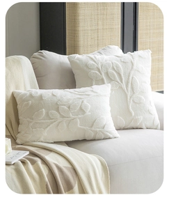 Detailed view of white plush pillows with embossed leaf patterns on a grey sofa