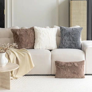 Textured leaf pattern plush throw pillows in coffee, cream and grey on a sofa