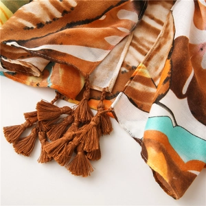 Detailed close-up of colorful leaf print cotton linen scarf with brown fringe tassels