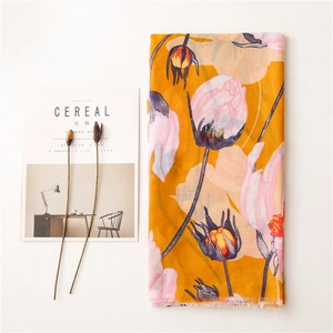 Detail of yellow cotton linen scarf with floral print and frayed edges on magazine