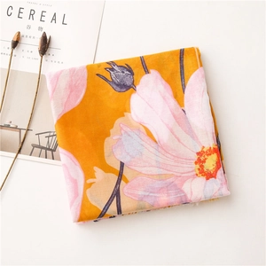 Detail of floral linen scarf with pink blossoms on a vibrant yellow and orange fabric