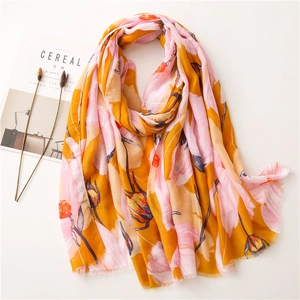 Detail of floral linen scarf with mustard and pink patterns next to a lifestyle magazine