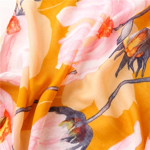 Macro detail of yellow linen scarf showing pink floral print and soft fabric texture