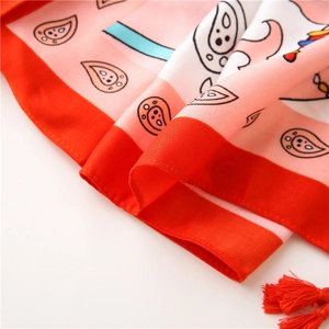 Detail of pink cotton linen scarf featuring paisley patterns and red handmade tassels